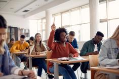 Jeune étudiante levant la main dans une salle de cours